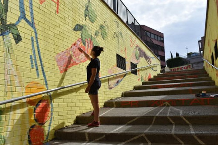 L'artista Sara Villarta Rodó pinta un mural plàstic a les escales d'accés al Mercat de Puigmercadal